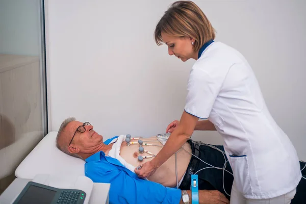 Kvinnlig (läkare) sjuksköterska utför Ekg test på en äldre man. — Stockfoto