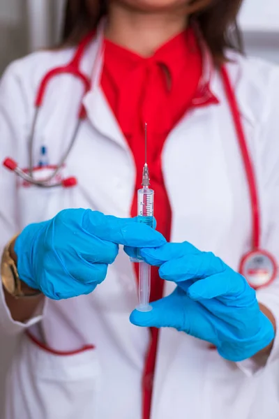 Acercamiento de una doctora (enfermera) sosteniendo una jeringa mientras está —  Fotos de Stock