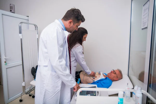 El médico (cardiólogo) está conectando sensores de vacío a un anciano —  Fotos de Stock