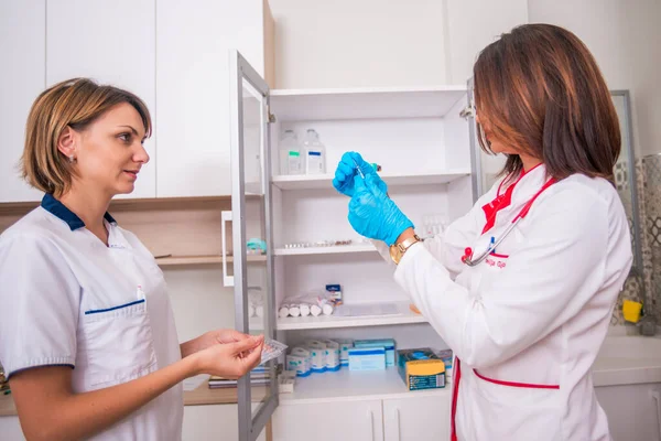 Ärztin hält eine Spritze in der Hand, während sie mit einem Arzt spricht — Stockfoto