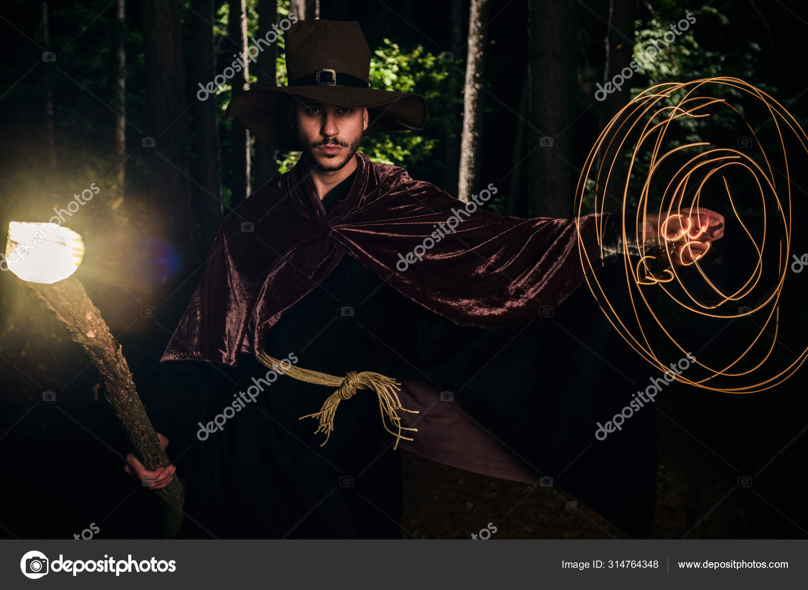 Человек В Волшебных Одеждах И Кепке, Держащий Светящийся Посох.