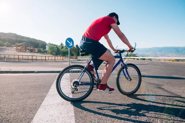 Passar manlig cyklist cykling rider sin cykel på en asfalterad väg — Stockfoto