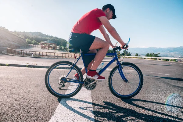 Apto ciclista ciclista masculino montando seu ciclo de bicicleta em uma estrada de asfalto — Fotografia de Stock