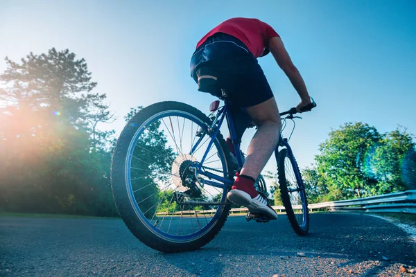 Fit mannelijke fietser fietser rijden zijn fiets op een asfaltweg — Stockfoto