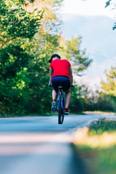 Fit cyklista jezdí na kole (kole) na prázdné silnici v přírodě — Stock fotografie