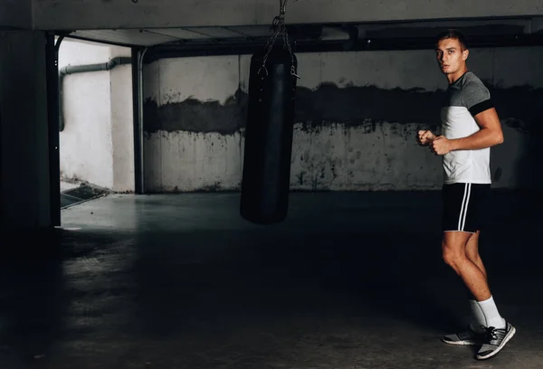 Muscles man training martial arts in underground garage