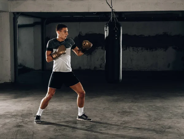ボクシング バッグ ラウンド 練習中に強力な前蹴りを与えて筋肉のハンサムな戦闘機 — ストック写真