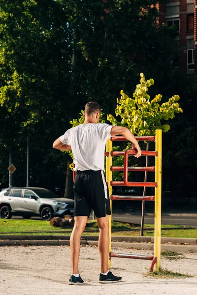 Muskulös man gör pull-ups på horisontell bar i stadspark — Stockfoto