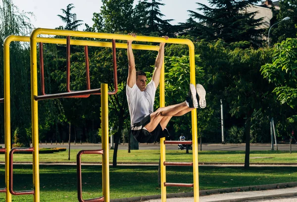 Unge man gör en pull-up på ribban i utomhus gym i — Stockfoto