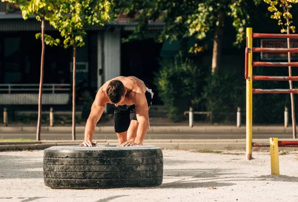 Trening crossfit - człowiek przerzucający oponę na obszarze miejskim — Zdjęcie stockowe