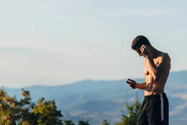 Sportieve man op zoek naar muziek op mobiele terwijl voor te bereiden op run — Stockfoto