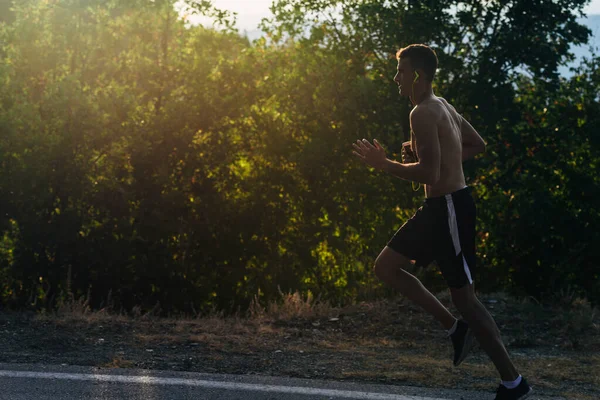 Jeune sprinter torse nu faire du jogging tout en écoutant de la musique sur — Photo