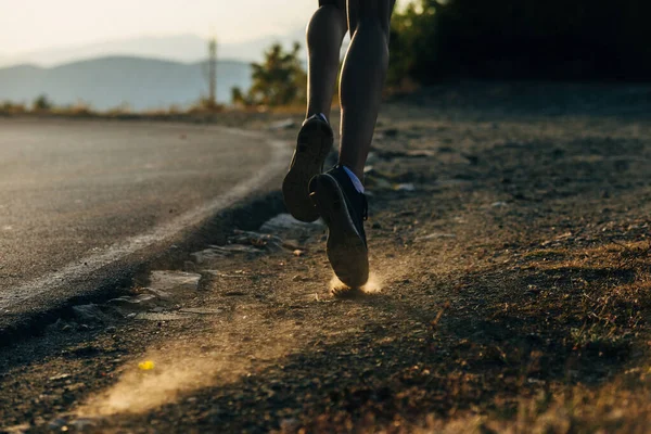 Vista posteriore di scarpe da ginnastica maschili che corrono sulla strada di montagna — Foto Stock