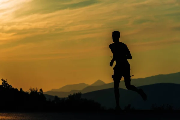 Спортивний чоловік біжить над блакитним небом на гірському шляху — стокове фото
