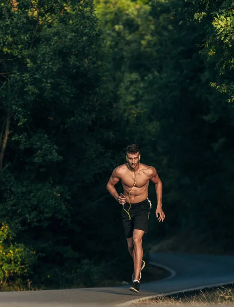 Crossfit man joggen met mobiele telefoon op de berg weg — Stockfoto