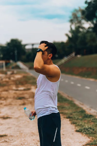 Sportieve man maakt zich klaar om te gaan rennen in een park en glimlachen — Stockfoto
