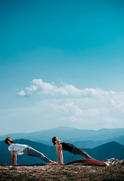 Dos personas practican yoga en las altas montañas — Foto de Stock