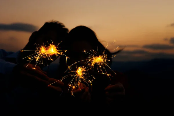 Jovem casal silhueta se divertindo com algum fogo de artifício no moun — Fotografia de Stock