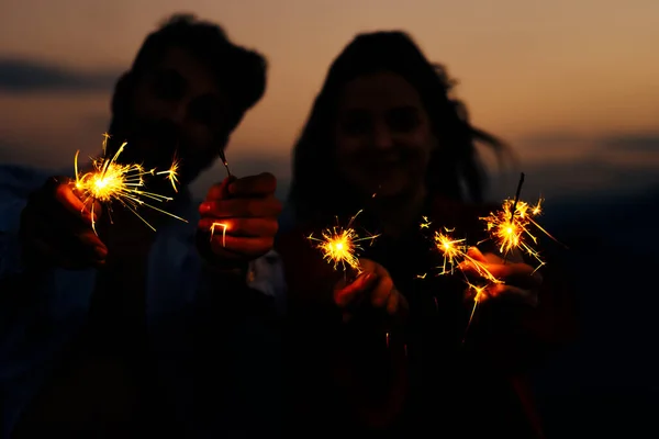 Sparklers nas mãos de um casal amoroso isolado no céu por do sol — Fotografia de Stock