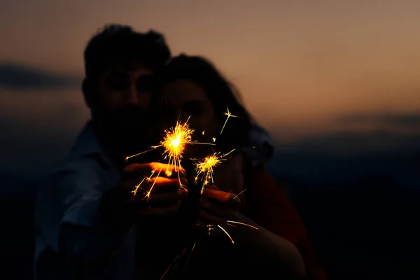 Frontansicht eines jungen kaukasischen Paares, das mit Feuerwerkskörpern spielt — Stockfoto