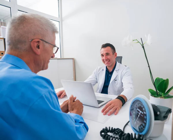 Schöner Doktor und sein älterer Patient im Gespräch — Stockfoto