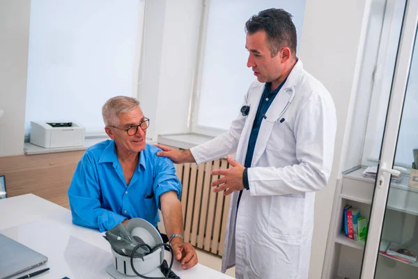 El médico caucásico de mediana edad le explica a su paciente mayor su situación. —  Fotos de Stock