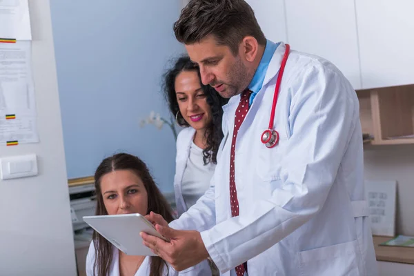 Two nurses ( female physicians ) and a male doctor looking in a — Stock Photo, Image