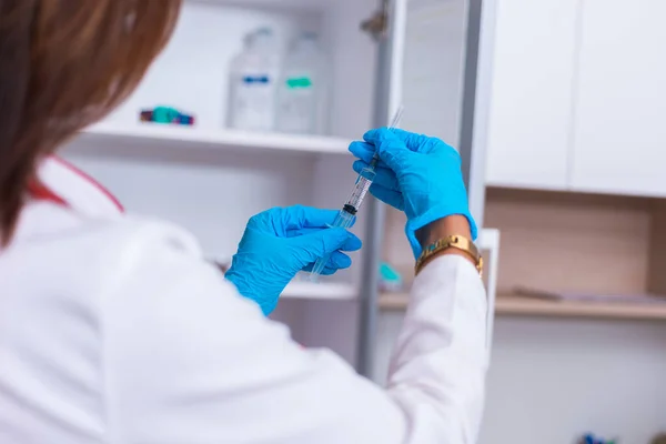 Acercamiento de una doctora (enfermera) sosteniendo una jeringa mientras está —  Fotos de Stock