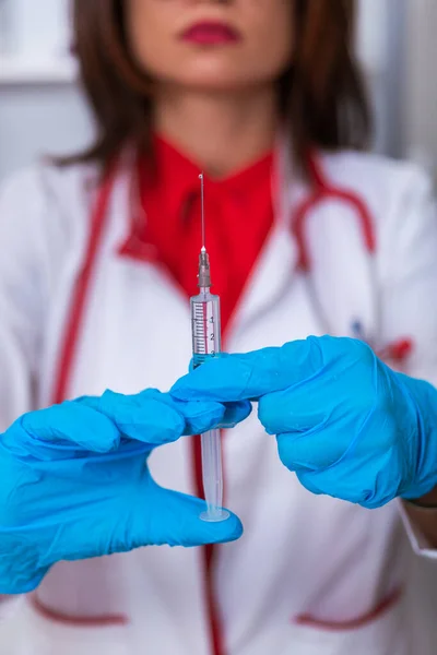 Acercamiento de una doctora (enfermera) sosteniendo una jeringa mientras está — Foto de Stock