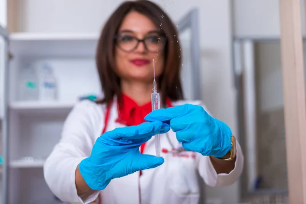 Acercamiento de una doctora (enfermera) sosteniendo una jeringa mientras está —  Fotos de Stock