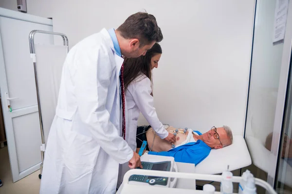 El médico (cardiólogo) está conectando sensores de vacío a un anciano —  Fotos de Stock