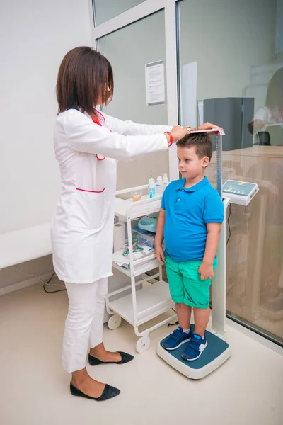Médico femenino midiendo la altura del niño en una clínica (h —  Fotos de Stock