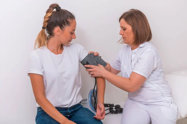 Médico femenino midiendo la presión arterial de su joven adolescente —  Fotos de Stock