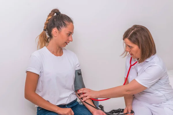 Médico femenino midiendo la presión arterial de su joven adolescente —  Fotos de Stock