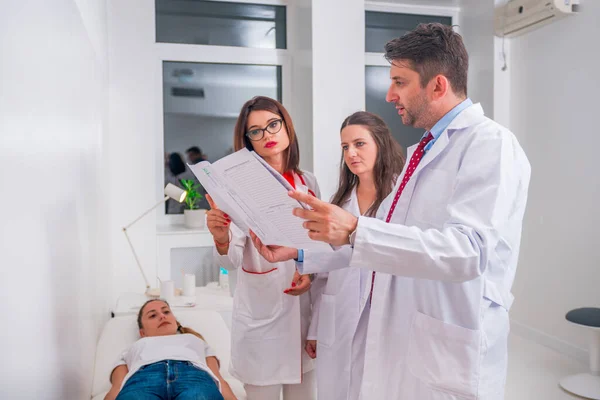 Grupo de médicos de pie junto a un paciente enfermo y discutiendo —  Fotos de Stock