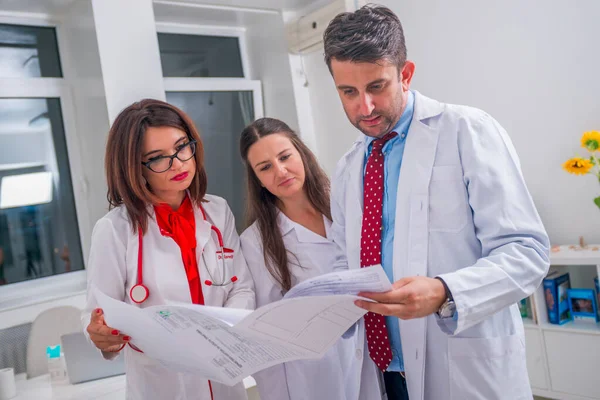 Gruppo di medici in piedi accanto a un paziente malato e discutere — Foto Stock