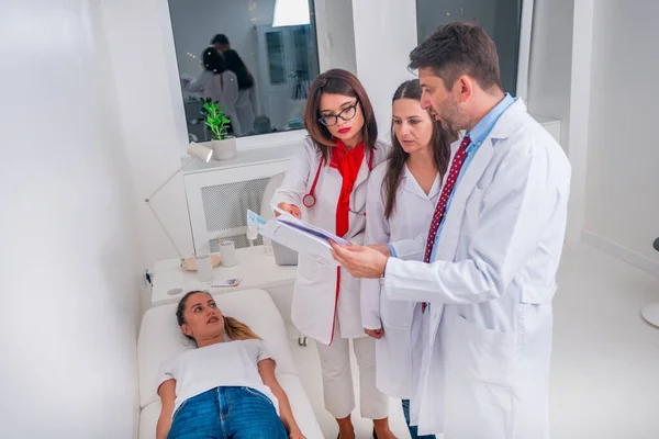 Grupa lekarzy stojąca obok chorego pacjenta i dyskutująca — Zdjęcie stockowe