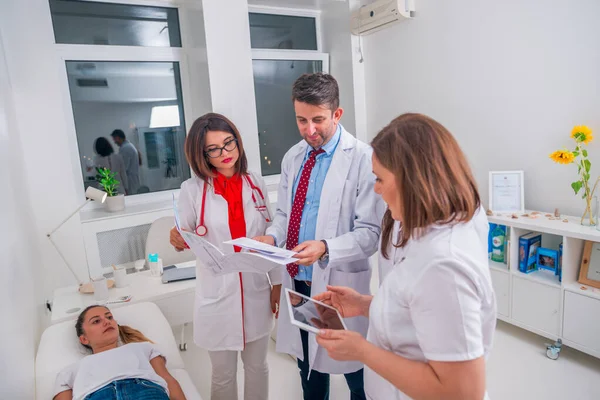 Grupo de médicos de pie junto a un paciente enfermo y discutiendo —  Fotos de Stock