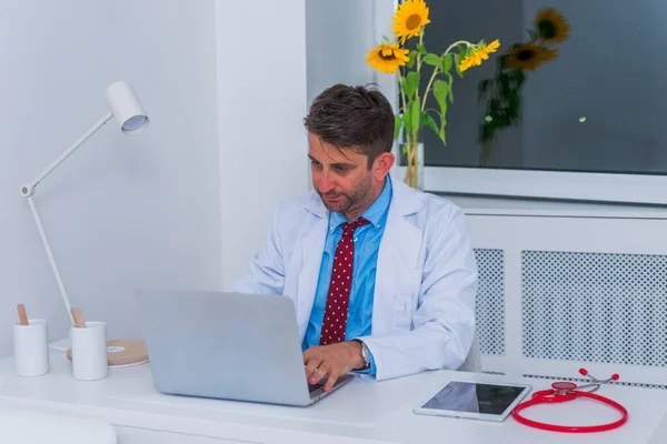 Männliche ernsthafte kaukasische Arzt sitzt in seinem Büro allein und th — Stockfoto