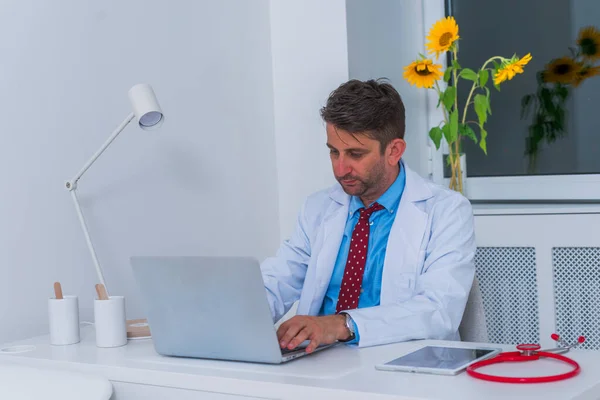 Hombre grave caucásico médico sentado en su oficina solo y th —  Fotos de Stock