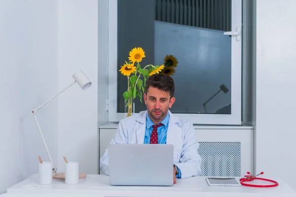 Mężczyzna poważne kaukaski lekarz siedzi w jego biuro sam i th — Zdjęcie stockowe