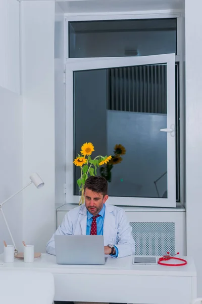 Männliche ernsthafte kaukasische Arzt sitzt in seinem Büro allein und th — Stockfoto