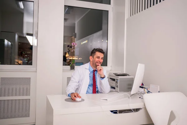 Retrato del médico especialista sentado en una silla en su escritorio whi —  Fotos de Stock