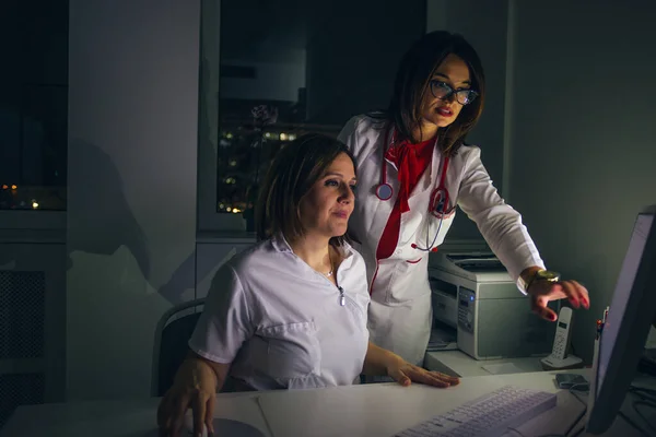Médicos femeninos (médicos) trabajan en una PC tarde en la noche . —  Fotos de Stock