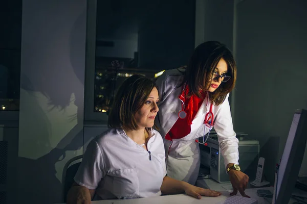 Médicos femeninos (médicos) trabajan en una PC tarde en la noche . —  Fotos de Stock