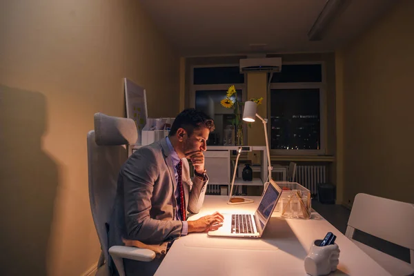 Ernsthafter Arzt arbeitet nachts an seinem Laptop (PC), Überstunden. — Stockfoto