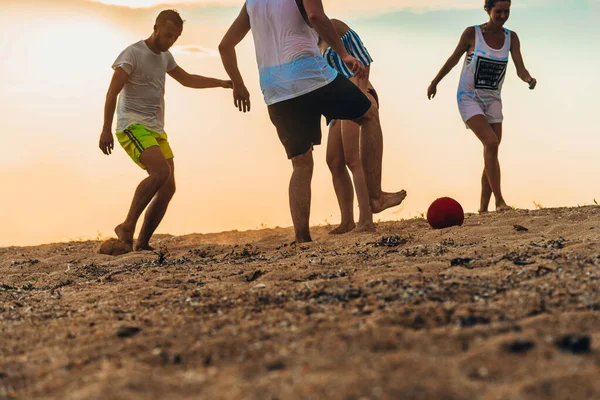 Группа друзей играет в футбол на песчаном пляже во время летнего отдыха — стоковое фото
