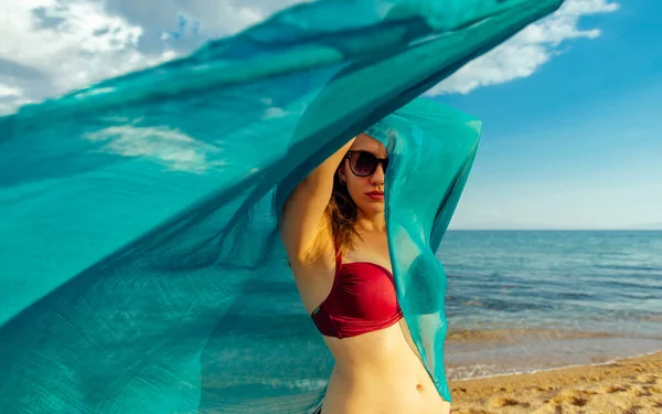 Young woman standing on sea beach with silk shawl — Stock Photo, Image