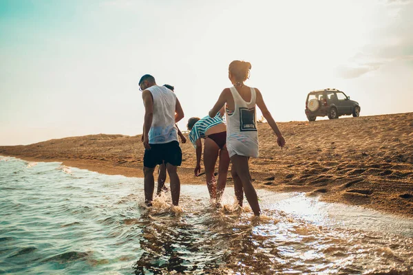 Gente disfrutando en el agua en la playa soleada al atardecer — Foto de Stock