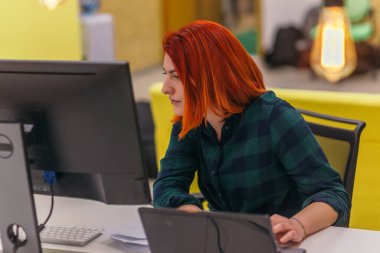 Redhead nerd at the office performing her daily routine task. clipart
